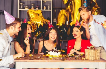 Charming female blowing on candles on birthday cake after making her wish at party.