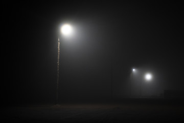 Street lights foggy misty night lamp post lanterns deserted road. Lonely street at night in the...