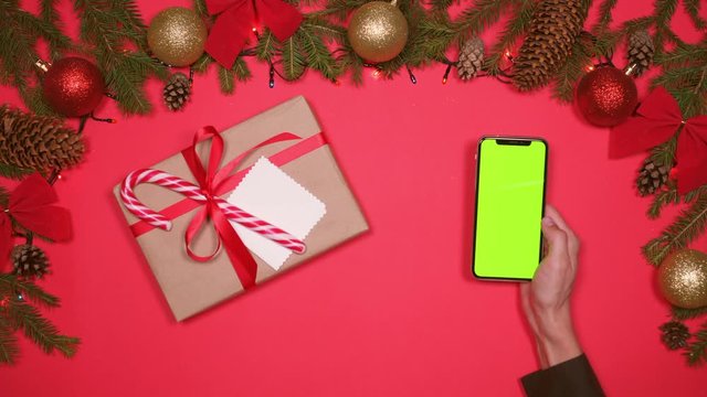 Hand using phone, Christmas decorations and gift box