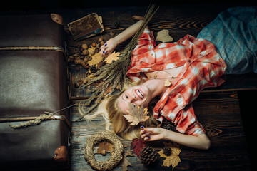 Fototapeta na wymiar Woman lies on wooden leaf background. Happy autumn people concept. Attractive young woman in a autumn seasonal clothes. Happy young woman are preparing for autumn sunny day.