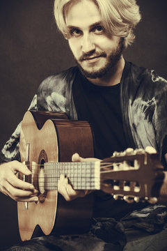 Blonde man playing acoustic guitar