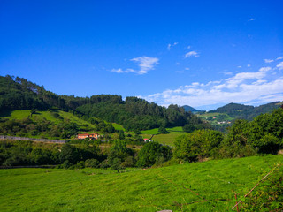 View of a valley around the mountains and green grass fields, with houses and buildings
