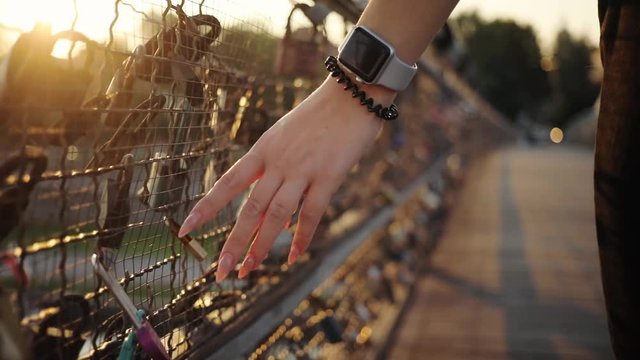 Close up view female hands with smart watch on the bridge with the locks display communication business internet contact clock electronic gadget interface sunset sunlight slow motion
