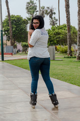 Very beautiful chubby woman with glasses happy with her inline skates in the park