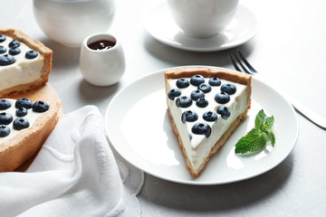Plate with piece of tasty blueberry cake on gray table