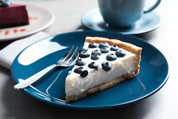 Plate with piece of tasty blueberry cake on gray table