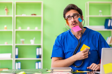 Young doctor sitting in hospital with many conflicting prioritie