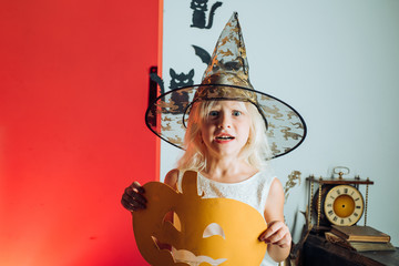 Happy halloween cute girl with pumpkins on a halloween background. Halloween party. Holiday child...