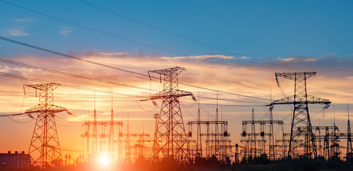 distribution electric substation with power lines and transformers, at sunset.