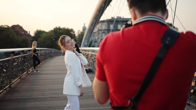 Close up young woman walk on bridge man take photo feel happy smile sunset sunlight couple female architecture background building canal city portrait slow motion