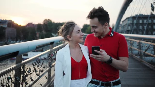 Happy couple using smartphone on bridge in city smile attractive beautiful handsome city lifestyle love man mobile phone boyfriend cell girlfriend together adult cellphone female portrait slow motion