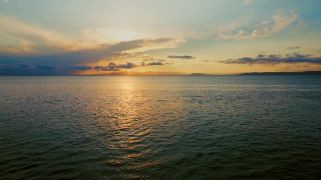 Sea view on a pleasant summer evening: a beautiful sunset, colored clouds, a pure sea with a yacht, the glint of the sun on the water. Sea, ocean, natural video for tourist, resort and meditative site