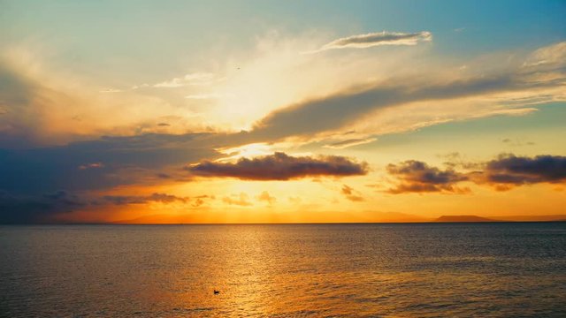 Sea view on a pleasant summer evening: a beautiful sunset, colored clouds, a pure sea with a yacht, the glint of the sun on the water. Sea, ocean, natural video for tourist, resort and meditative site