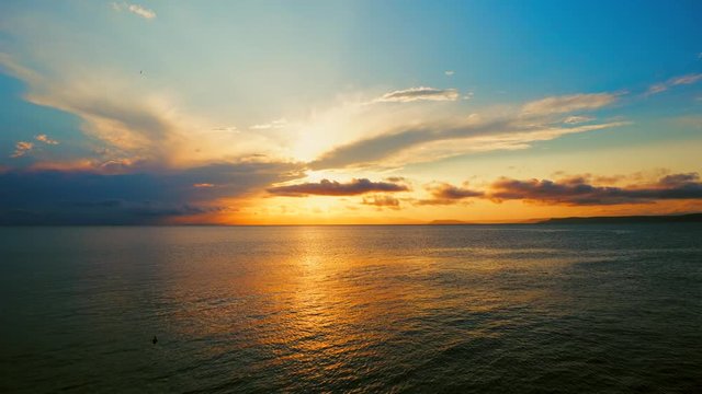 Sea view on a pleasant summer evening: a beautiful sunset, colored clouds, a pure sea with a yacht, the glint of the sun on the water. Sea, ocean, natural video for tourist, resort and meditative site