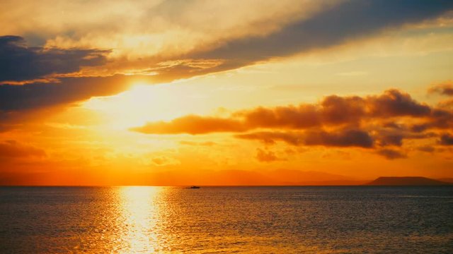 Sea view on a pleasant summer evening: a beautiful sunset, colored clouds, a pure sea with a yacht, the glint of the sun on the water. Sea, ocean, natural video for tourist, resort and meditative site
