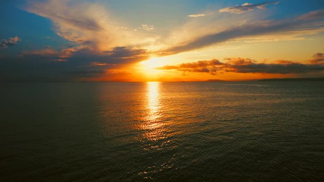 Sea view on a pleasant summer evening: a beautiful sunset, colored clouds, a pure sea with a yacht, the glint of the sun on the water. Sea, ocean, natural video for tourist, resort and meditative site