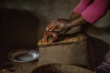 African woman making peanut butter in her home hut.