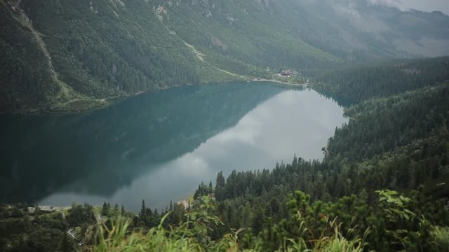 beautiful blue mountain lake with green forest and high mountains in the background Morskie Oko - Poland europe hill landscape nature peak rock sky tatra close up slow motion