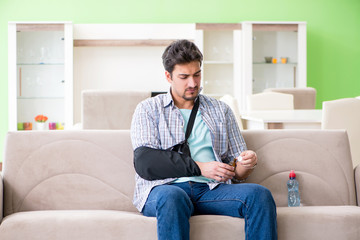 Young student man with hand injury sitting on the sofa 