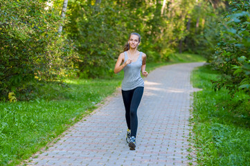 Fototapeta na wymiar Running woman atletic spotsman trains in the summer park. Outdoor fitness portrait