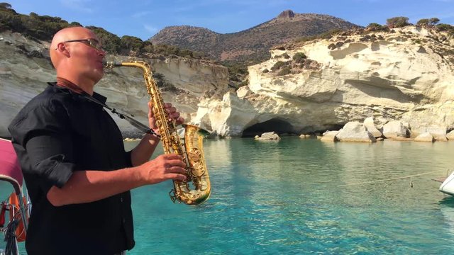 The saxophonist plays on a yacht that swims the sea