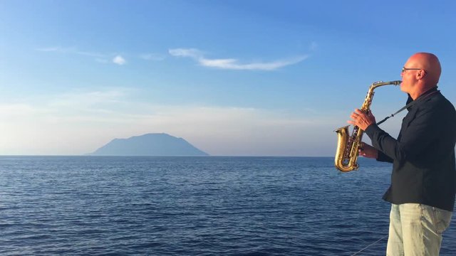 The saxophonist plays on a yacht that swims the sea view of the islands