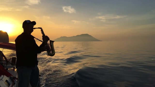 Saxophone player sunset silhouette from yaht