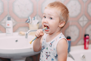 Little child toddler boy brushing his teeth in bathroom