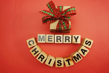 top view of merry christmas alphabet letter with gift box on red background