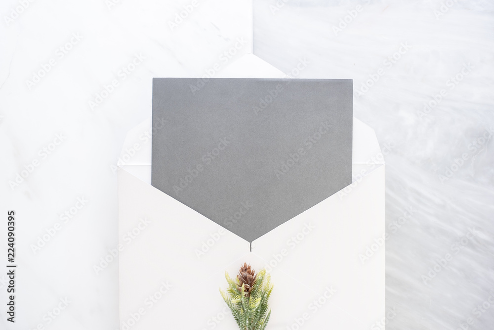 Poster Top view of blank grey card in white envelop with pine leaf on two layer step of marble table top.Mock up template for display of design.modern business items.