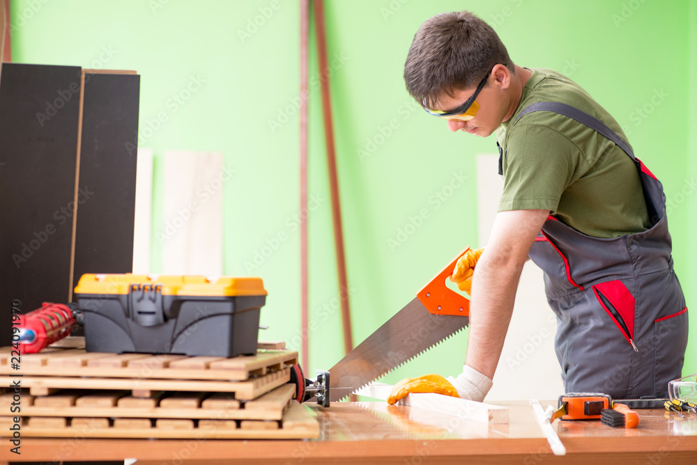 Wall mural Young man carpenter working in workshop 