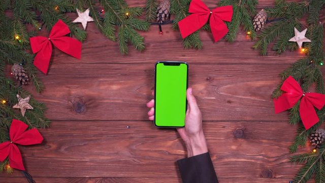 Hand placing smartphone on Christmas background