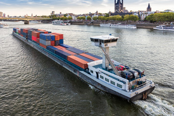 A large barge loaded with shipping containers floating on the river Rhine in Cologne. - obrazy, fototapety, plakaty