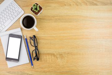 Smartphone,keyboard ,notebook and  essential tools items on wooden desk.