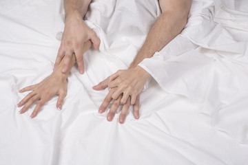 Couple holding hands while having sex in bed.