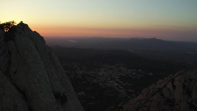 Video from above, aerial view oa a spectacular sunset behind some granite mountains. San Pantaleo village in the background, Sardinia, Italy.
