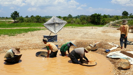 Arbeiter suchen in Wasser, Sand und Kies auf einem Diamantfeld nach Diamanten in Borneo