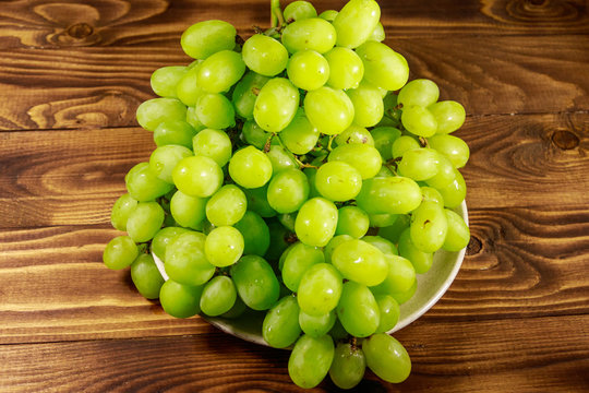 Tasty fresh white grape in a plate on wooden table