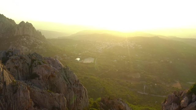 Video from above, aerial view oa a spectacular sunset behind some granite mountains. San Pantaleo village in the background, Sardinia, Italy.