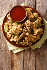 Delicious crispy deep-fried chicken stomachs and tomato sauce close-up on a plate. Vertical top view