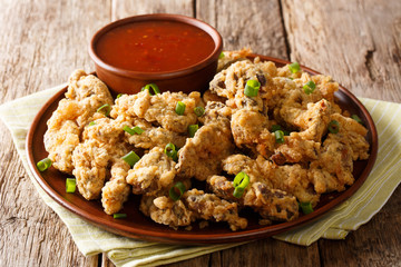 Spicy crispy fried chicken gizzards served with green onions and spicy tomato sauce close-up. horizontal