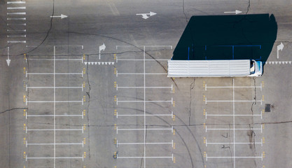 Parking lot, marking parking spaces with a long truck and shadows from all objects located on it on a sunny summer day.