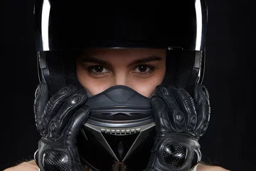 Badkamer foto achterwand Motorsport Mooie jonge vrouw in zwarte leerhandschoenen en beschermende motorhelm in studio. Aantrekkelijke, zelfbewuste vrouwelijke motorcoureur die handen en lichaam beschermt tegen vallen en ongevallen