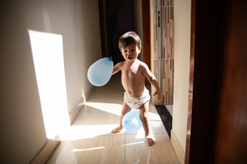 Cute baby boy toddler - Playing with two blue balloons at home