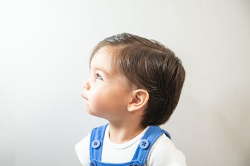 Naklejka premium Cute baby boy toddler - with blue romper on white background - Looking at light