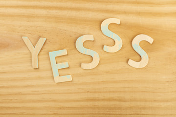 Yes, letters forming word on a wooden background with copyspace