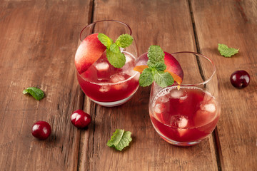 A photo of vibrant red drinks with cherries on a rustic background with copy space