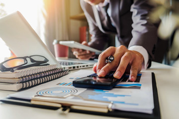 Fototapeta premium Businessman calculates financials with graph paper on the table on the cost of home office in the evening.