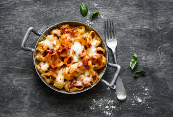 Tomato sauce mac and cheese, baked in vintage pan on a wooden dark background, top view