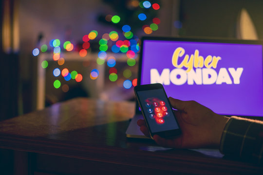hand hold smartphone at night near laptop, cyber monday design concept f